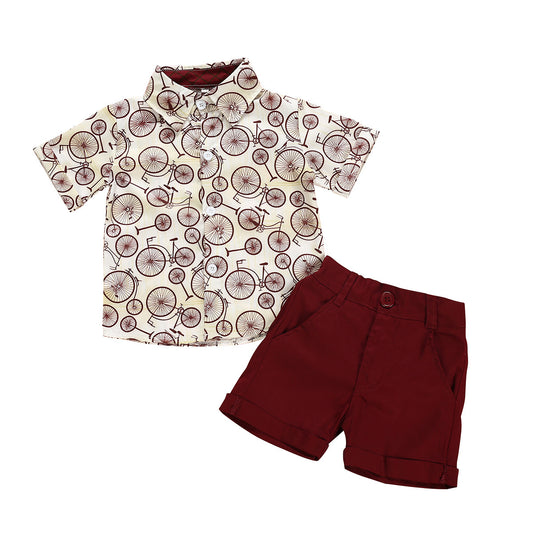 Young boy in a summer outfit featuring a bicycle print shirt and wine red shorts.