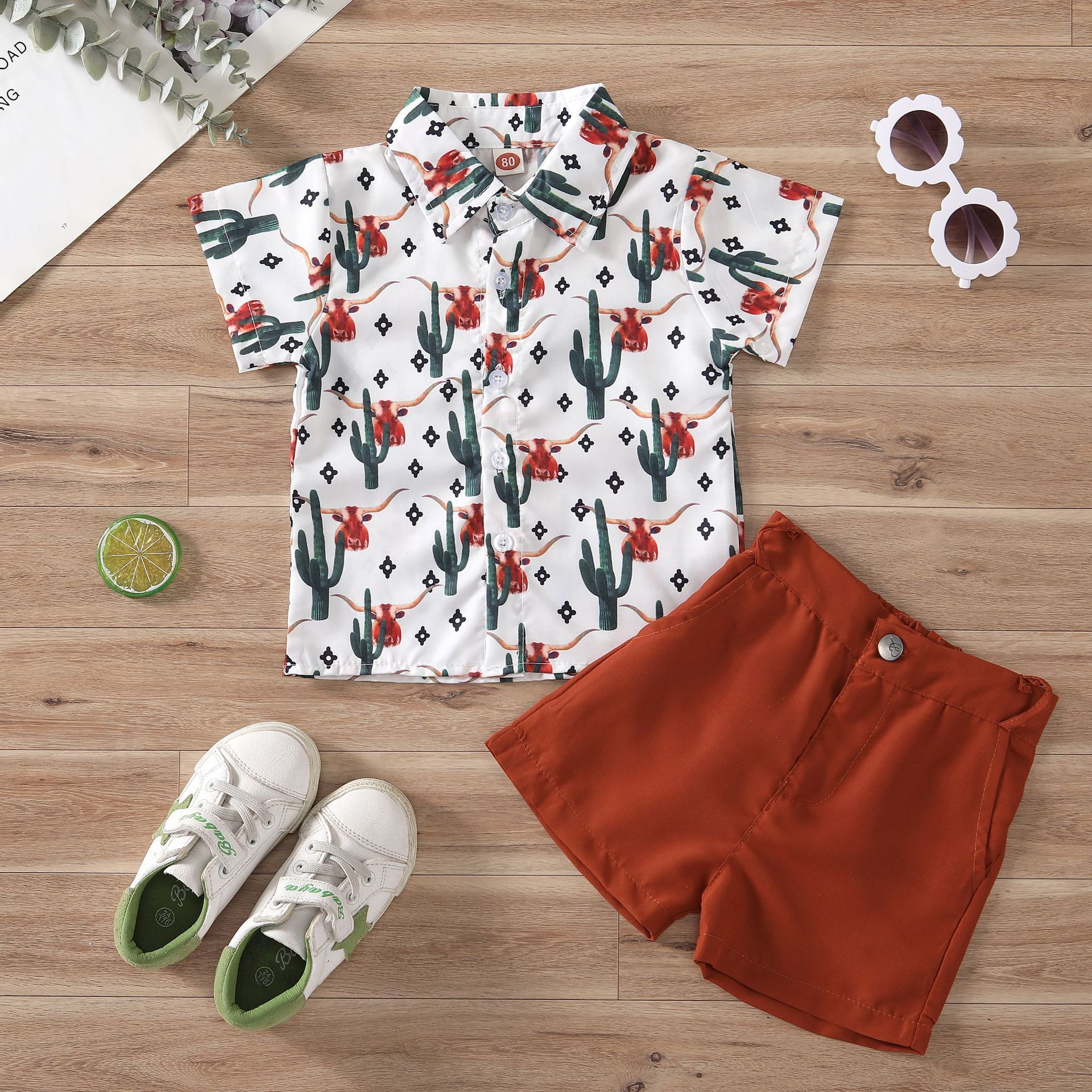 Two-piece Hawaiian-style outfit for kids. Short-sleeved shirt features a tropical print, paired with coordinating shorts. Perfect for summer vacations or luau parties